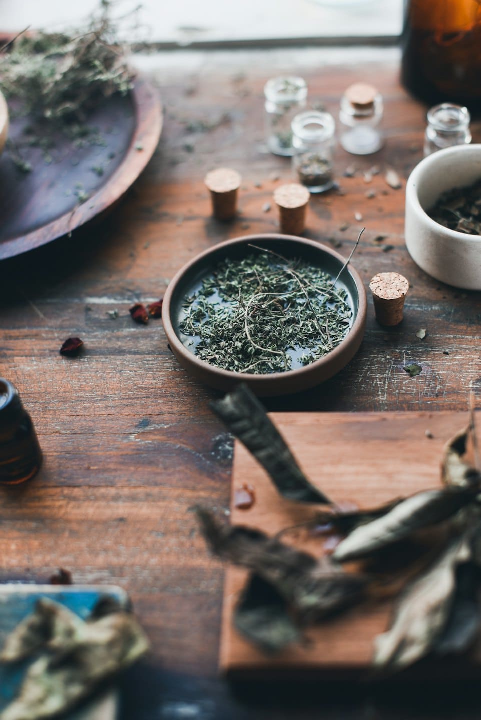 Dried herbs and apothecary bottles arranged on a wooden table.