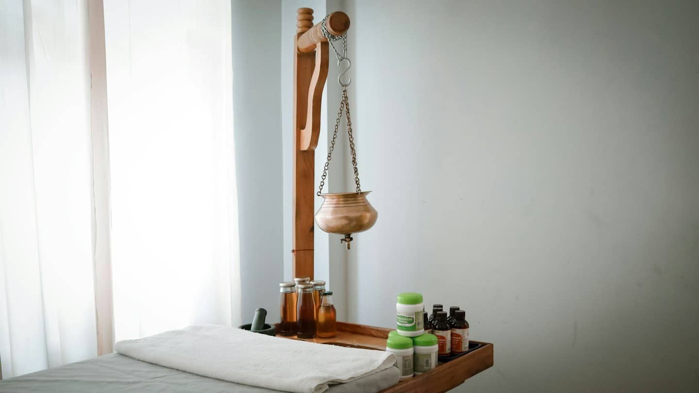 Shirodhara pot hangs over a massage table in a spa.
